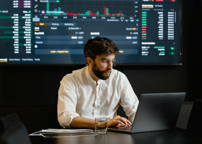 Investment analyst reviewing financial data on multiple screens