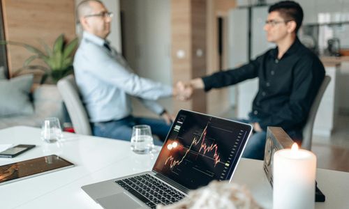 Investment deal closing handshake in modern office